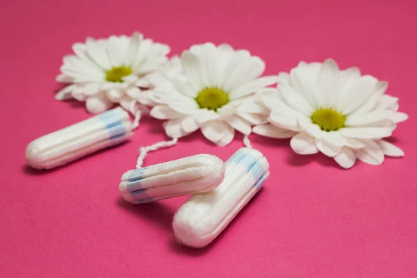 Tampones higiénicos y flores blancas sobre un fondo rosa . —  Fotos de Stock