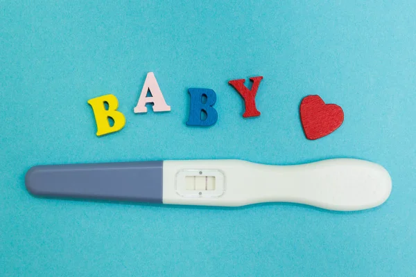 Позитивний тест на вагітність з двома смужками і словом "дитина" на синьому фоні . — стокове фото