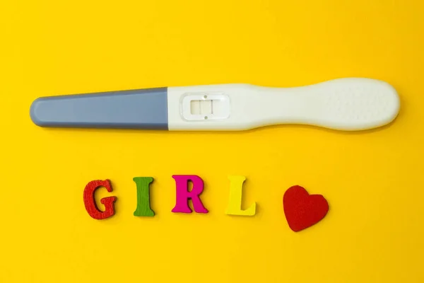 Positive pregnancy test with two strips and the word "girl" on a yellow background. — Stock Photo, Image