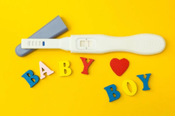Позитивний тест на вагітність, серце і слово "дитина і хлопчик" на жовтому тлі . — стокове фото