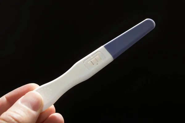 White is a positive pregnancy test on a black background in a male hand. — Stock Photo, Image