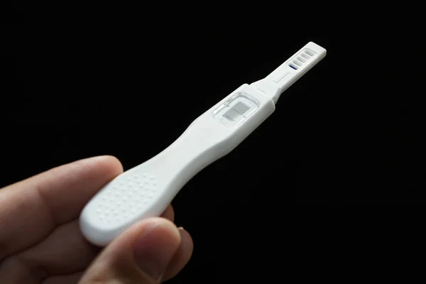 Positive pregnancy test on a black background in a male hand. — Stock Photo, Image