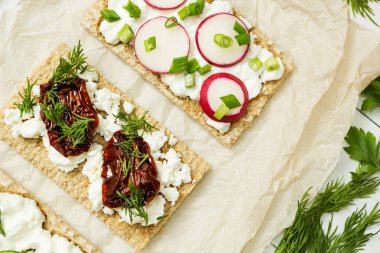 Meze Beyaz ahşap zemin üzerinde kağıt üzerinde keçi peyniri üzerinden. Süzme peynir, turp, peyniri, kurutulmuş domates ve yeşillik.