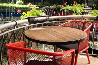 Dokulu arka plan bulanık önünde boş ahşap masa. Çiçekler, bitkiler ve bir çeşme - ışık sokak kafe görüntülemek veya ürün yüklemek için kullanılabilir. Ürünü görüntülemek için bir düzen.