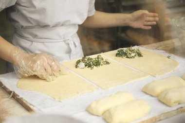Kadınların elleri çiğ hamurdan turtalar hazırlıyor..