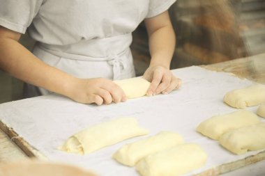 Kadınların elleri çiğ hamurdan turtalar hazırlıyor..