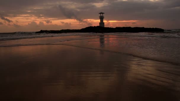 Vuurtoren met golven bij zonsondergang. — Stockvideo