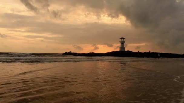 Vuurtoren met golven bij zonsondergang. — Stockvideo