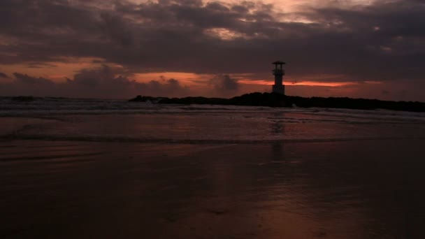 Vuurtoren met golven bij zonsondergang. — Stockvideo