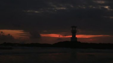 Deniz feneri günbatımı, dalgalar ile.