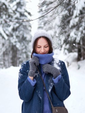 Esmer, gri şapkalı, mavi kazaklı ve mavi ceketli, kış ormanlarında yürüyor..