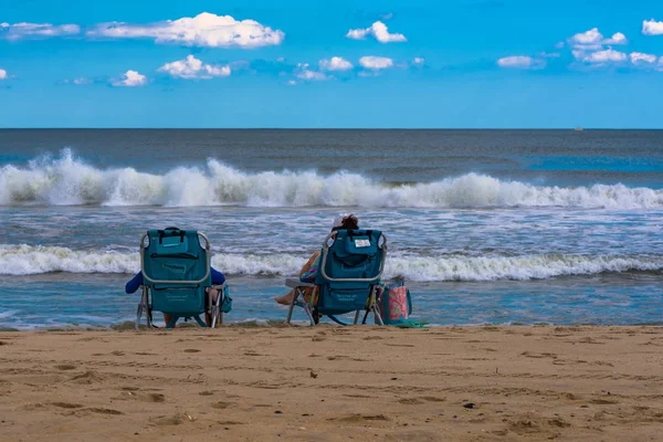 Люди, сидящие на краю океана — стоковое фото