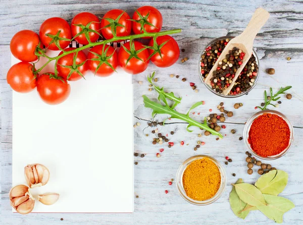 Horizontal food banner with cherry tomatoes, garlic, peppercorns, spice and notebook on wooden background. Empty space for text.