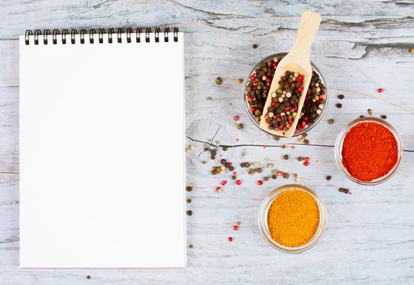 Horizontal food banner with peppercorns, spice and notebook on wooden background. Empty space for text.