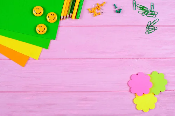 Gula och gröna pennor, fiberpennor, brevpapper, Gem, brevpapper naglar, filt och leenden på rosa trä bakgrund — Stockfoto
