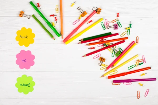 Lápices coloridos y rotuladores, papel de anotador de color, clips de papel, clavos de papelería sobre fondo de madera blanco —  Fotos de Stock