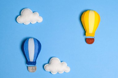 Mavi gökyüzünde bulutlar, çerçeve, boşaltmak ile sıcak hava balonu. El yapımı keçe oyuncak.