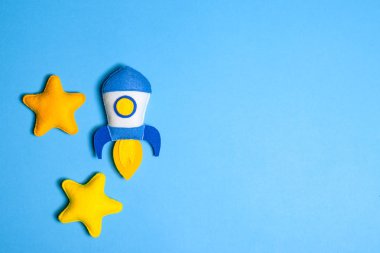 Roket çıkartıyor. El yapımı keçe oyuncak. Uzay gemisi Sundown arka plan üzerinde sarı yıldız.