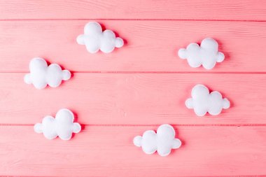Çerçeve, pembe ahşap zemin üzerine boşaltmak ile zanaat beyaz bulutlar. El yapımı keçe oyuncak. Soyut gökyüzü.