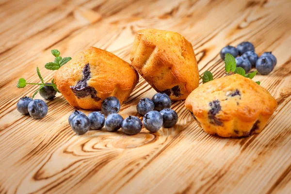 Blueberry muffin. Homemade baked cupcake with blueberries, fresh berries, mint on wooden background. Empty space for text.