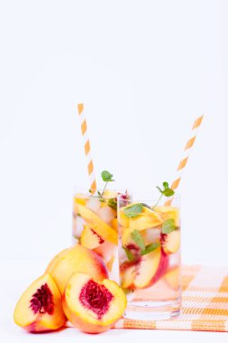 Buz ve nane yaprakları ile şeftali limonata. Ev yapımı limonata, beyaz ve turuncu olgun olgun nektarin. Şeftali çay iki kadeh. Beyaz ahşap zemin üzerinde serinletici yaz içeceği.