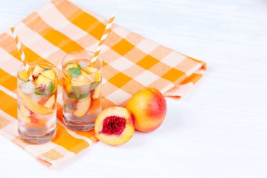 Buz ve nane yaprakları ile şeftali limonata. Ev yapımı limonata, beyaz ve turuncu olgun olgun nektarin. Şeftali çay iki kadeh. Beyaz ahşap zemin üzerinde serinletici yaz içeceği.