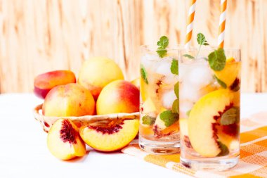 Buz ve nane yaprakları ile şeftali limonata. Ev yapımı limonata, beyaz ve turuncu olgun olgun nektarin. Şeftali çay iki kadeh. Ahşap arka plan üzerinde serinletici yaz içeceği.