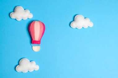 Mavi gökyüzünde bulutlar, çerçeve, boşaltmak ile sıcak hava balonu. El yapımı keçe oyuncak.