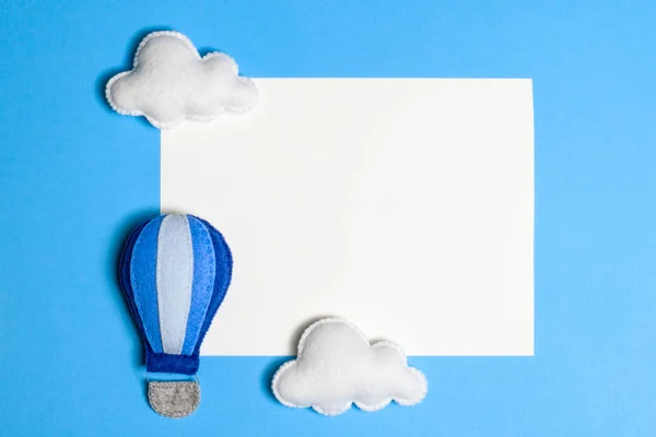 Globo de aire caliente en el cielo azul con nubes, marco, copyspace. Juguetes de fieltro hechos a mano . —  Fotos de Stock