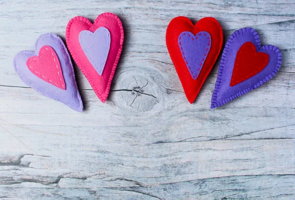 Hand made felt colorful hearts on wooden background — Stock Photo, Image