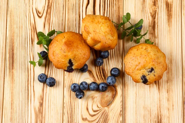 Homemade baked muffin with blueberries, fresh berries, mint on wooden background. Empty space for text.