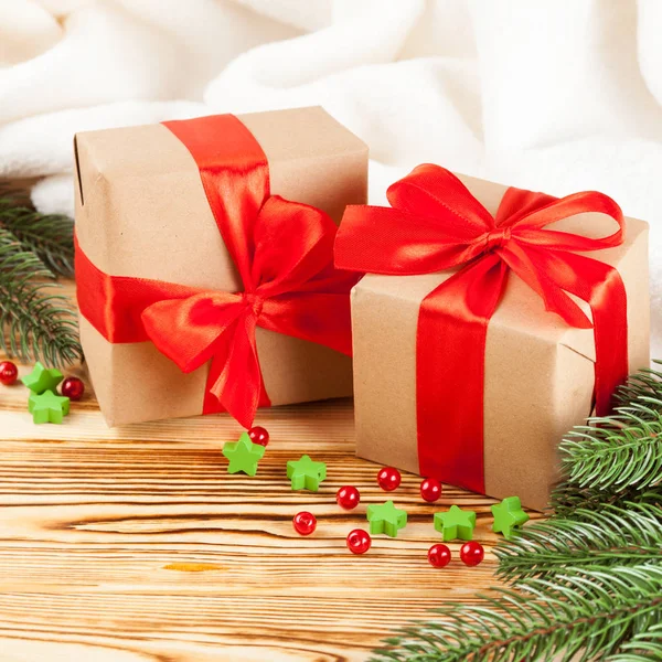 Ahşap arka plan üzerinde kırmızı kurdele ve yay, yeşil Noel ağacı, Dekorasyon, beyaz ekose ile el sanatları Hediyelik kutu. Noel ve yeni yıl kutlama kartı, afiş, el ilanı.