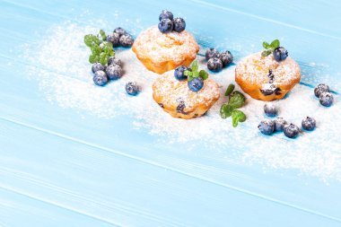 Böğürtlenli kek. Ev yapımı kek yaban mersini ile pişmiş, taze çilek, mavi ahşap zemin üzerine pudra şekeri. Üstten Görünüm.