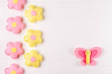 Zanaat pembe ve sarı kelebek ve çiçek, boşaltmak Beyaz ahşap zemin üzerinde. El yapımı keçe oyuncak. Soyut gökyüzü.