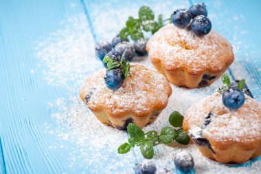 Böğürtlenli kek. Ev yapımı kek yaban mersini ile pişmiş, taze çilek, mavi ahşap zemin üzerine pudra şekeri. Üstten Görünüm.