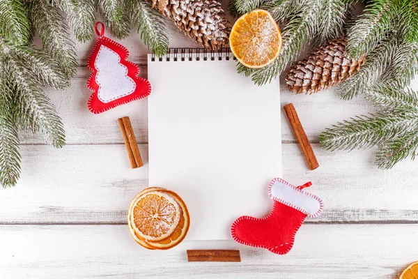 Banner de Navidad con árbol verde, conos, naranja, canela y cuaderno sobre fondo de madera blanca . — Foto de Stock