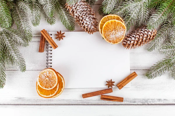 Banner de Navidad con árbol verde, conos, naranja, canela y cuaderno sobre fondo de madera blanca . — Foto de Stock