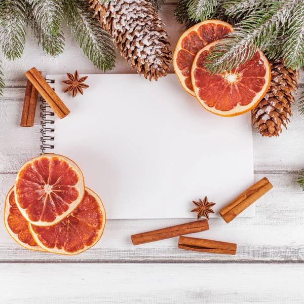 Banner de Navidad con árbol verde, conos, naranja, canela y cuaderno sobre fondo de madera blanca . — Foto de Stock