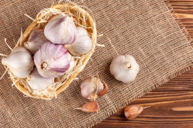 Sarımsak yatay banner. Eko tarım kavramı. Bütün sarmısakları ve Sivas'tan kahverengi ahşap doku arka plan üzerinde parçası üzerinde hasır sepet karanfil. Organik gıda.