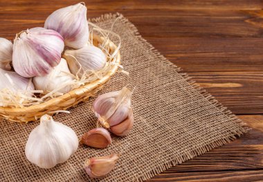 Sarımsak yatay banner. Eko tarım kavramı. Bütün sarmısakları ve Sivas'tan kahverengi ahşap doku arka plan üzerinde parçası üzerinde hasır sepet karanfil. Organik gıda.