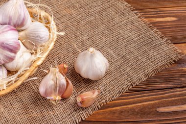 Sarımsak yatay banner. Eko tarım kavramı. Bütün sarmısakları ve Sivas'tan kahverengi ahşap doku arka plan üzerinde parçası üzerinde hasır sepet karanfil. Organik gıda.