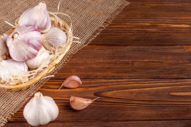 Sarımsak yatay banner. Eko tarım kavramı. Bütün sarmısakları ve Sivas'tan kahverengi ahşap doku arka plan üzerinde parçası üzerinde hasır sepet karanfil. Organik gıda.