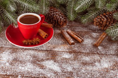 Yeşil ağaç, koniler, sıcak çikolata, kırmızı dekorasyonu, kahverengi ahşap arka plan üzerine tarçın ile kırmızı cup ile yılbaşı banner