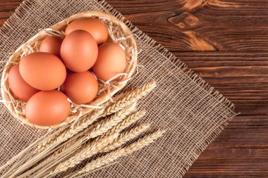 Tavuk yumurta yatay banner. Eko tarım kavramı. Kırmızı yumurta ve buğday kulaklar kahverengi ahşap dokulu arka plan üzerine Sivas'tan parçası üzerinde. Organik gıda.