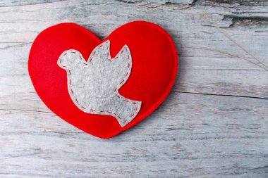 Kalp üzerinde ahşap arka plan yaptı gri güvercin, kırmızı el hissettim