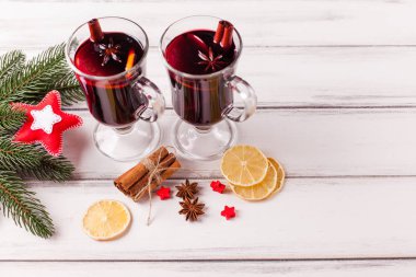 Kış yatay mulled şarap afiş. Gözlük sıcak kırmızı şarap ve baharat, ağaç, ahşap arka plan üzerinde keçe süslemeleri ile.