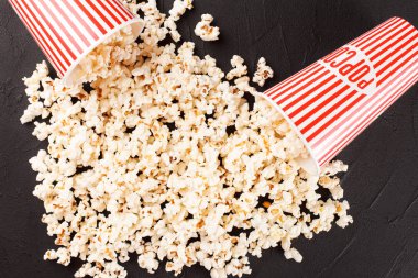 Patlamış mısır yatay banner. Kırmızı kağıt bardak ve koyu arka plan üzerinde yalan çekirdekleri elimden. Kopya alanı.