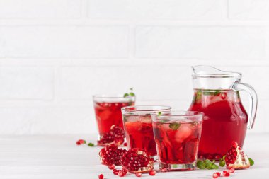 Nar buz ve güzel gözlük ve sürahi, taze olgun nar Beyaz ahşap zemin üzerine nane kokteyli. Tatlı kırmızı suyu. Fotoğraf kadar kapatın. Seçici odak