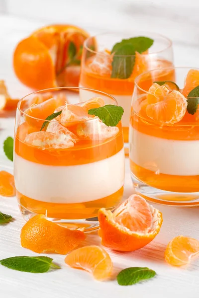 Smetanové panna cotta s oranžové želé v krásné brýle, čerstvé zralé mandarinka, na bílém pozadí dřevěná. Italský zákusek. Detailní fotografie. Selektivní fokus. — Stock fotografie