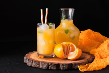 Mandarin buz ve güzel gözlük ve sürahi, Beyaz ahşap zemin üzerinde olgunlaşmış taze narenciye nane kokteyli. Tatlı portakal suyu. Fotoğraf kadar kapatın. Seçici odak